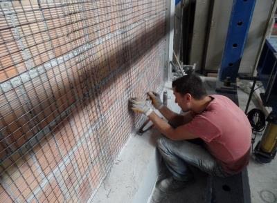 Hasır çelik tel uygulamasında tipik güçlendirme yöntemlerinin aksine hasır çelik tel betonarme çerçeveye tutturulmamış, duvarın iki yüzünden karşılıklı olarak bağ teli ile birbirine bağlanmıştır.