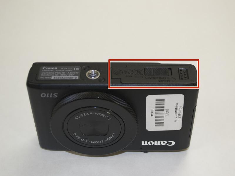 Adım 1 Lens kameranın altındaki pil kapağını açık kaydırarak pil