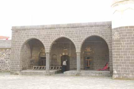 Sol kısmında ise yuvarlak kemerli mihrabiye ile kapının sağ ve solunda üstünde siyahbeyaz taşlardan, sağır, üç dilimli bir pencere yer almaktadır (Foto:25-26).