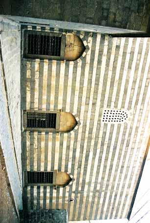 Taç kapının iki yan kenarında mahfil bölümlerine çıkışı sağlayan düz atkı taşlı birer kapı açıklığı ile mihrabiye bulunmaktadır. Atkı taşlarının üstünde iki renkli taş işçiliği görülmektedir.